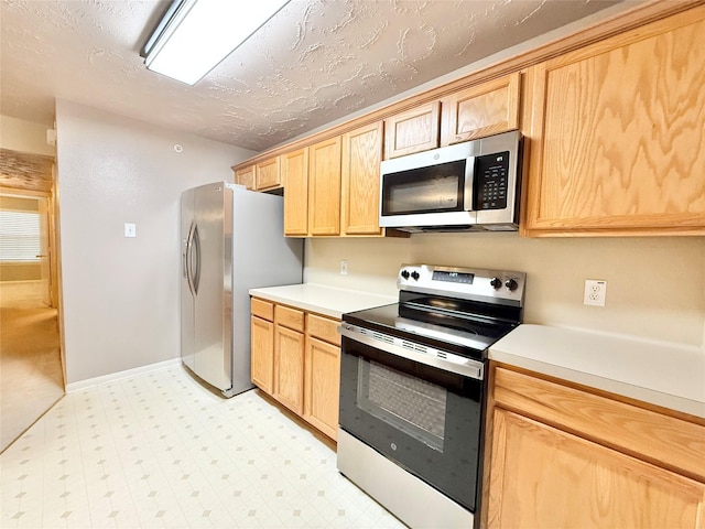 8051 Bay Branch Dr Unit 424, The Woodlands, TX 77382 - kitchen with light brown cabinetry, appliances with stainless steel finishes, light floors, and light countertops