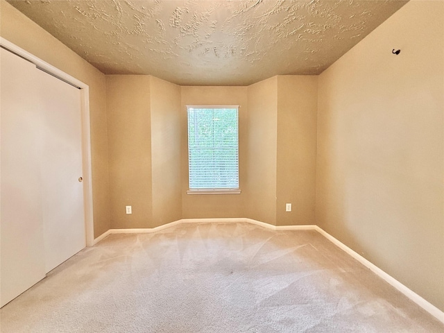 carpeted empty room with a textured ceiling and baseboards
