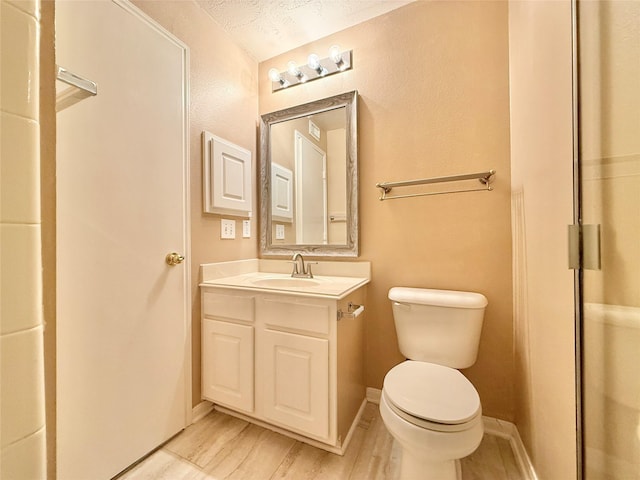 bathroom featuring toilet, a textured ceiling, and vanity
