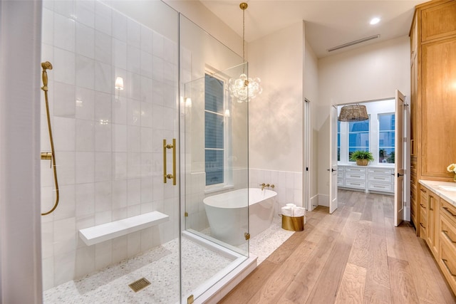 bathroom featuring a shower stall, vanity, hardwood / wood-style flooring, visible vents, and a soaking tub