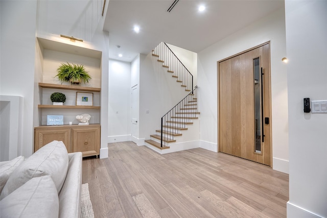 interior space with light wood-type flooring, baseboards, recessed lighting, and stairs