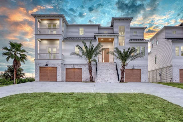 view of front facade featuring a standing seam roof, driveway, a garage, and a balcony