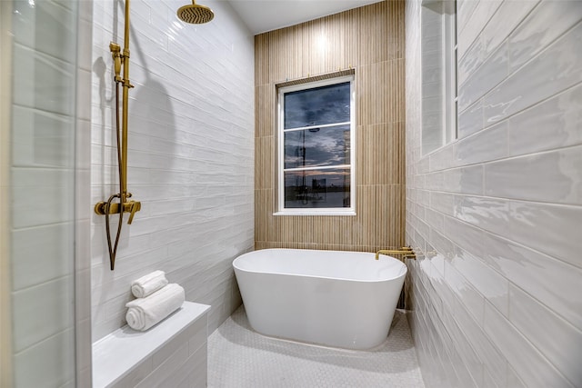 bathroom featuring a tile shower, a freestanding bath, and tile walls