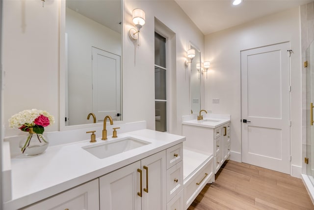 bathroom with recessed lighting, two vanities, wood finished floors, and a sink