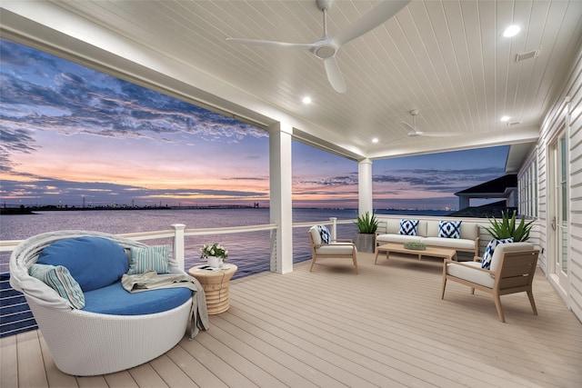 deck at dusk featuring visible vents, ceiling fan, a water view, and an outdoor hangout area