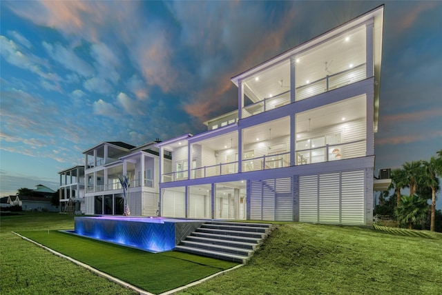 rear view of house with a pool, a yard, and a balcony