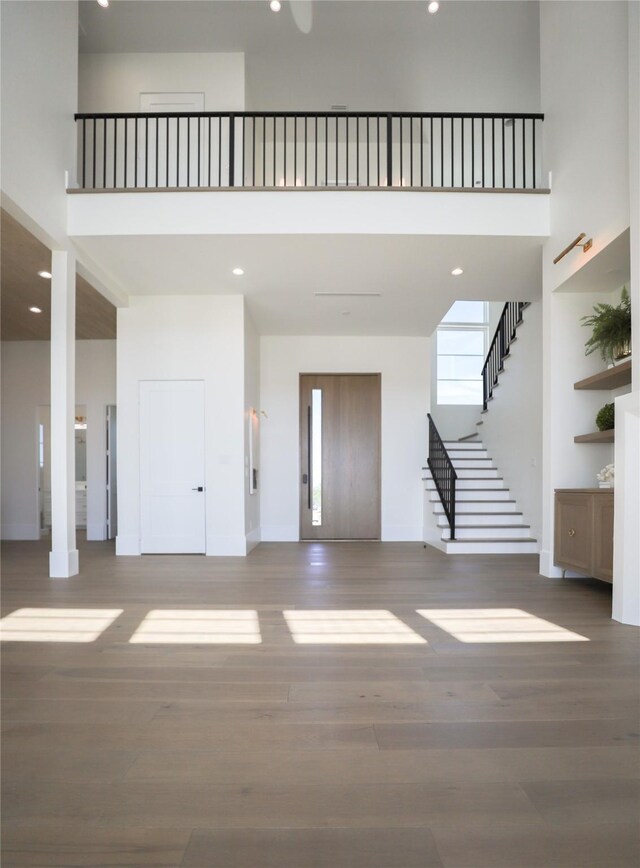 426 81st St, Galveston, TX 77554 - unfurnished living room with recessed lighting, wood finished floors, stairs, baseboards, and a high ceiling