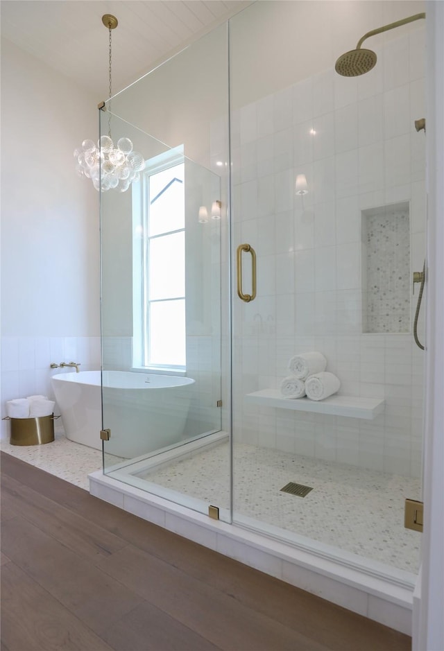 426 81st St, Galveston, TX 77554 - full bathroom with a shower stall, a freestanding bath, tile walls, wood finished floors, and a notable chandelier