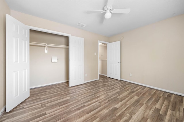 unfurnished bedroom with a closet, a ceiling fan, visible vents, baseboards, and wood finished floors