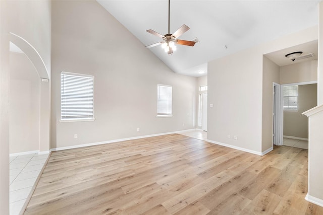 spare room with light wood finished floors, ceiling fan, high vaulted ceiling, and baseboards