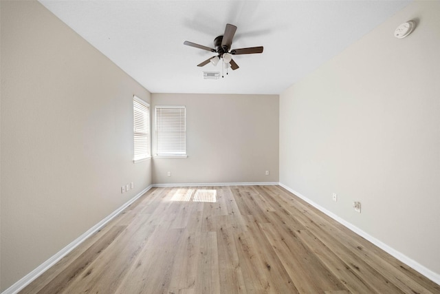 empty room with a ceiling fan, visible vents, light wood-style flooring, and baseboards