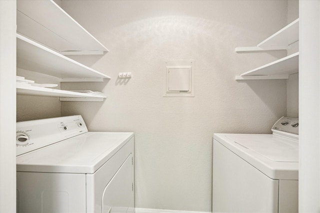 laundry room with electric panel, washing machine and clothes dryer, and laundry area