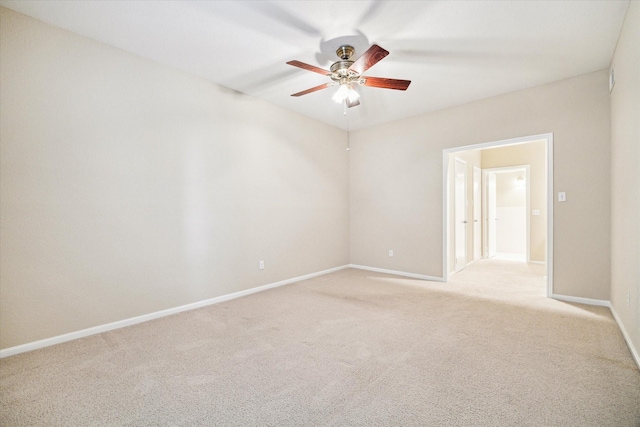spare room featuring light colored carpet, ceiling fan, and baseboards