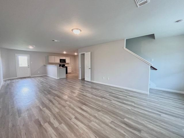 312 N Orange St, Sweeny, TX 77480 - unfurnished living room featuring baseboards, light wood-style flooring, and stairs