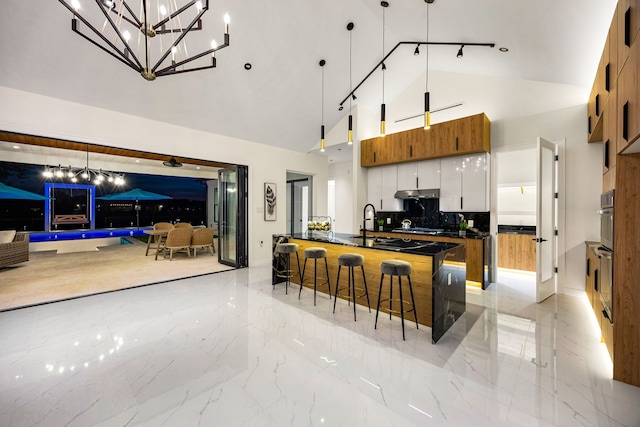 kitchen with marble finish floor, dark countertops, high vaulted ceiling, brown cabinets, and tasteful backsplash