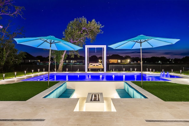 pool at night with fence, an outdoor fire pit, a fenced in pool, a patio, and a yard