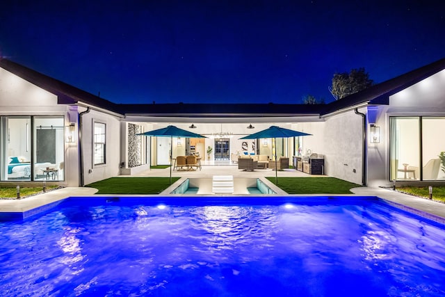 back of house at twilight featuring a patio, an outdoor pool, stucco siding, and an outdoor hangout area