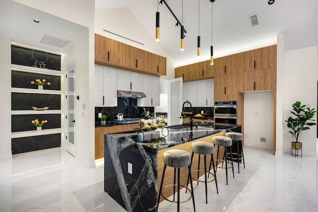 kitchen featuring brown cabinetry, a sink, marble finish floor, and visible vents
