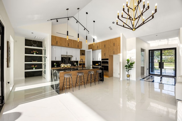 kitchen with brown cabinets, a spacious island, high vaulted ceiling, and open floor plan