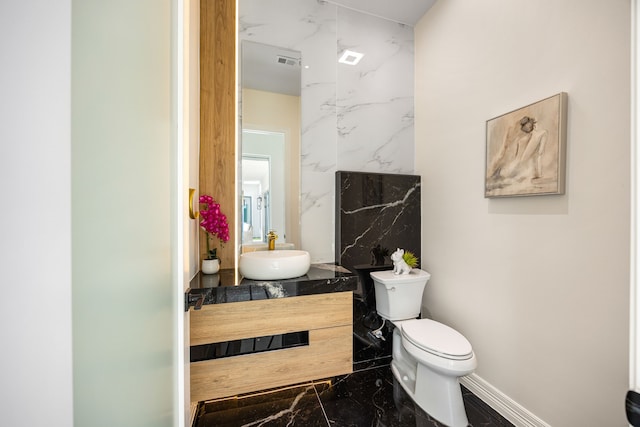 half bath featuring visible vents, vanity, baseboards, toilet, and marble finish floor