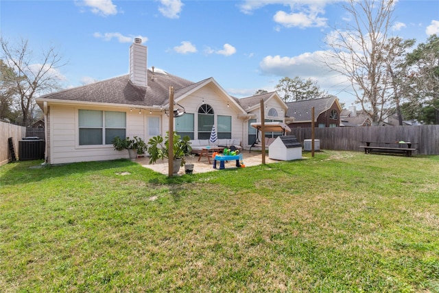 back of property with a fenced backyard, cooling unit, a chimney, a patio area, and a yard