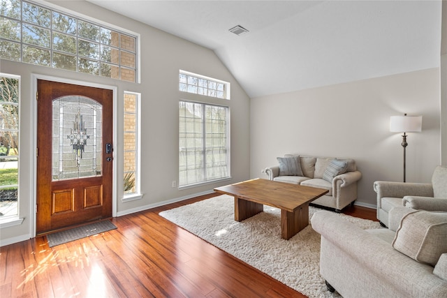 living room featuring vaulted ceiling, wood finished floors, visible vents, and baseboards