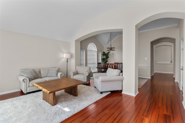 living area featuring dark wood finished floors, baseboards, arched walkways, and vaulted ceiling