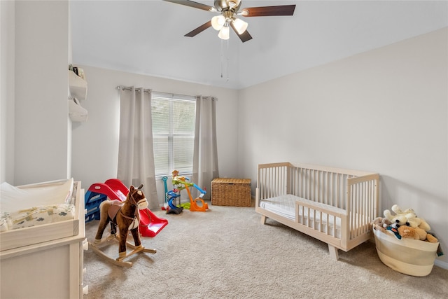 bedroom featuring ceiling fan, carpet floors, lofted ceiling, and a crib