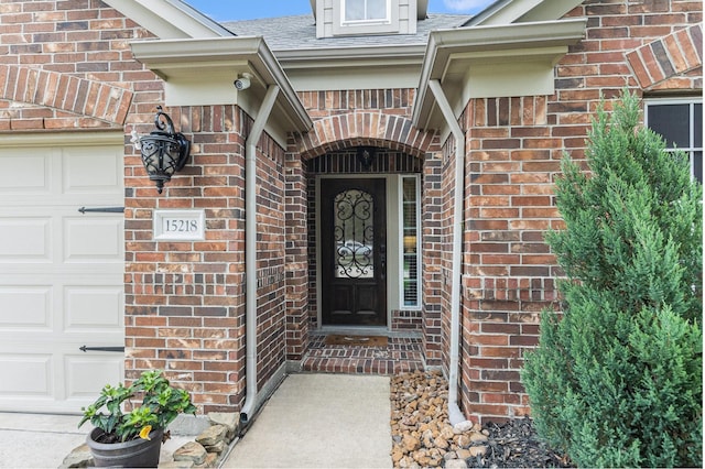 property entrance featuring brick siding, a shingled roof, and an attached garage