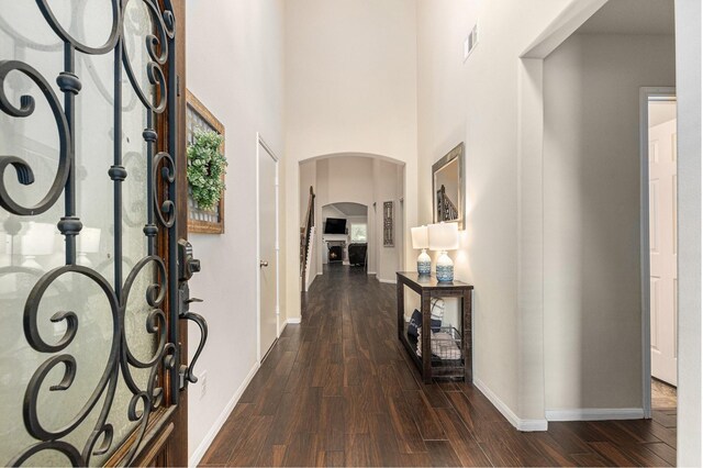 foyer entrance featuring arched walkways, baseboards, dark wood finished floors, and visible vents