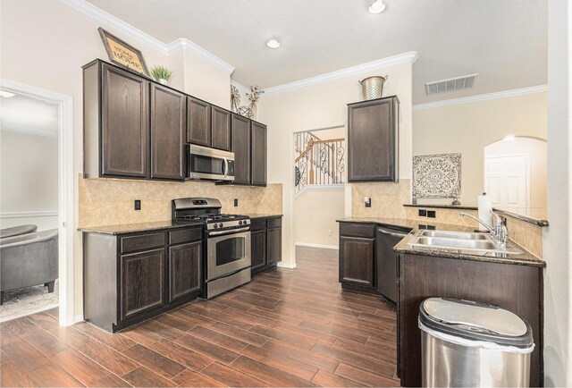 kitchen featuring stainless steel appliances, ornamental molding, a sink, and dark brown cabinets