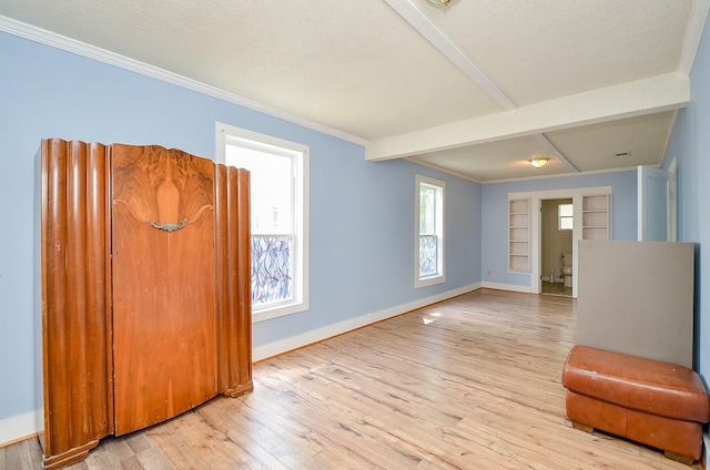 interior space with ornamental molding, a textured ceiling, baseboards, and light wood-style floors