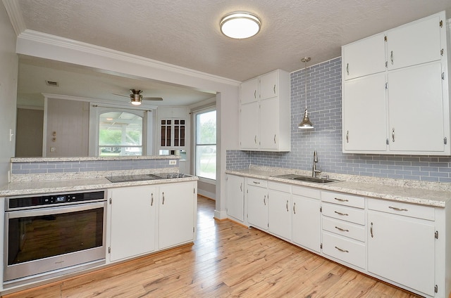 kitchen with ornamental molding, black electric cooktop, a sink, and stainless steel oven