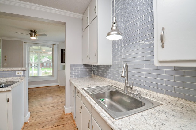 kitchen with white cabinets, a sink, light countertops, light wood finished floors, and backsplash