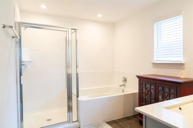 bathroom with recessed lighting, wood finished floors, a bath, vanity, and a stall shower