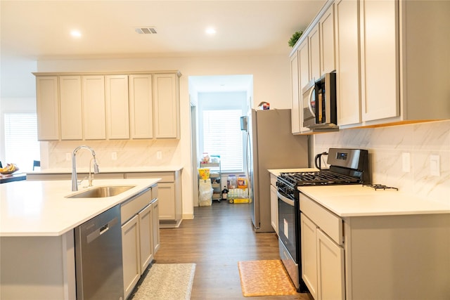 kitchen featuring light wood finished floors, a sink, decorative backsplash, stainless steel appliances, and visible vents