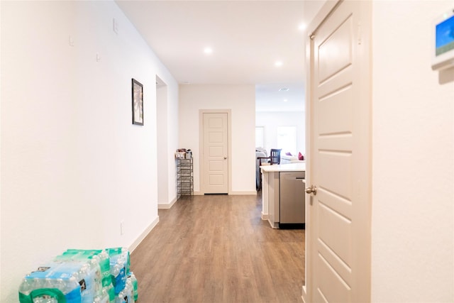 hallway with baseboards, recessed lighting, and light wood-style flooring