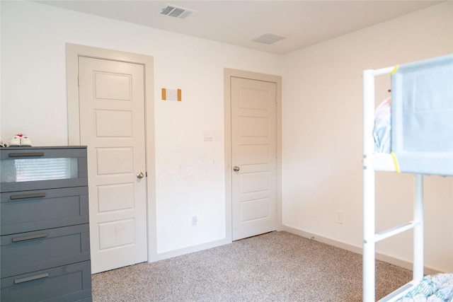 unfurnished bedroom featuring visible vents, light colored carpet, and baseboards