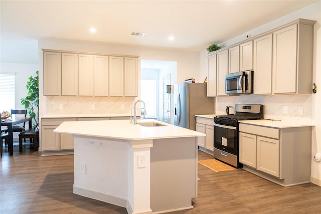 kitchen featuring appliances with stainless steel finishes, tasteful backsplash, a kitchen island with sink, and a sink