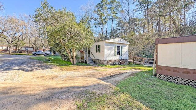 view of side of home with dirt driveway, an outbuilding, and a lawn
