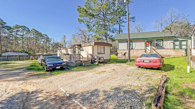 view of front of home featuring brick siding, a deck, and fence