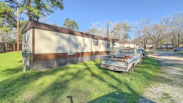 view of side of home featuring fence and a lawn