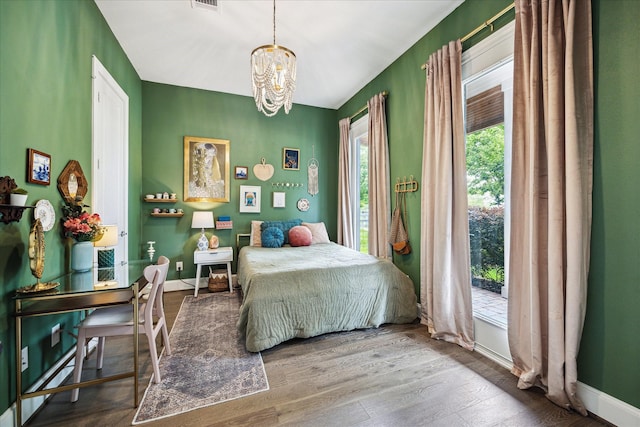 bedroom with an inviting chandelier, wood finished floors, visible vents, and access to outside