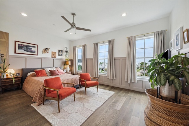 bedroom featuring wood finished floors, a decorative wall, recessed lighting, and wainscoting