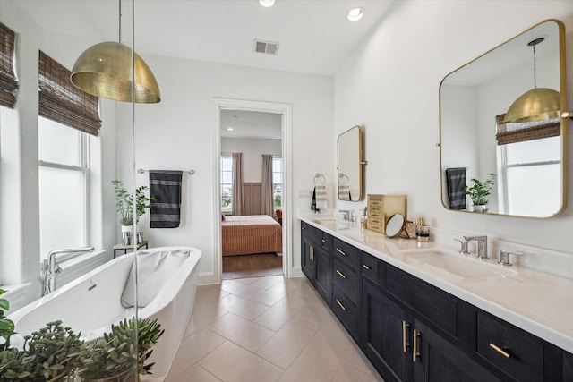 ensuite bathroom with a sink, a freestanding bath, ensuite bath, and visible vents