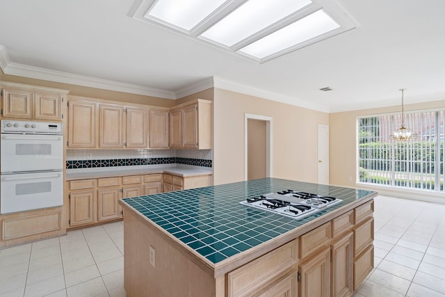 kitchen with light tile patterned floors, light brown cabinetry, an inviting chandelier, tile countertops, and white appliances