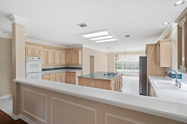 kitchen with light brown cabinets, double oven, a center island, a sink, and visible vents