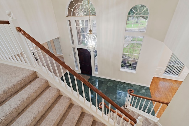 staircase with a towering ceiling and a notable chandelier