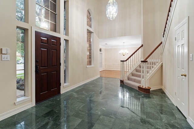 entrance foyer featuring stairway, a chandelier, baseboards, and a high ceiling