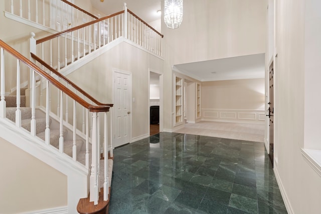stairway with baseboards, a high ceiling, and a decorative wall